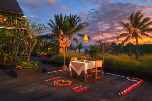 a table with chairs and flowers on a wooden deck at Swarga Suites Bali Berawa, Marclan Collection in Canggu