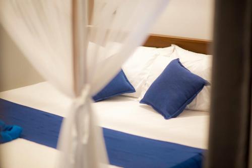 a bed with blue and white pillows in a room at Chathu Villa in Walgama South