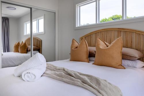 a bedroom with two beds with pillows and a mirror at Olas Villa 5 - Plunge Pool & Walk to Beach in Anna Bay