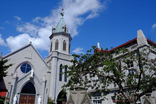 a church with a tower with a cross on it at ステラサイト函館 in Hakodate