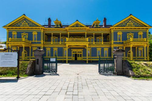 a large yellow house with a gate in front at ステラサイト函館 in Hakodate