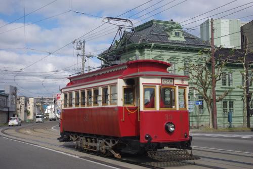 a red trolley car driving down a street at ステラサイト函館 in Hakodate