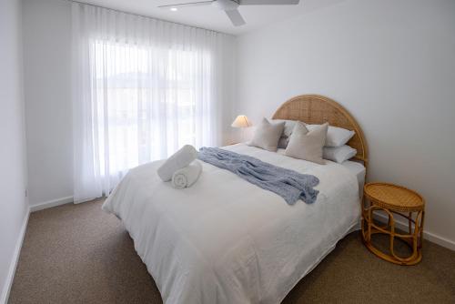 Un dormitorio con una gran cama blanca con una gran ventana. en Olas Villa 4 - Plunge Pool & Walk to Beach, en Anna Bay