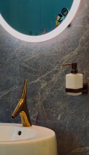 La salle de bains est pourvue d'un lavabo avec un robinet en or et un miroir. dans l'établissement 2 bhk luxury independant heritage villa, à Trivandrum