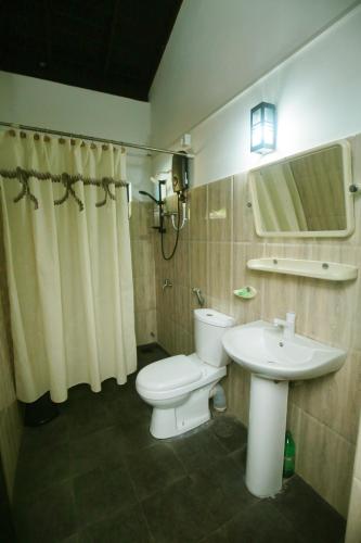 a bathroom with a white toilet and a sink at Soluna Ocean Villa in Tangalle