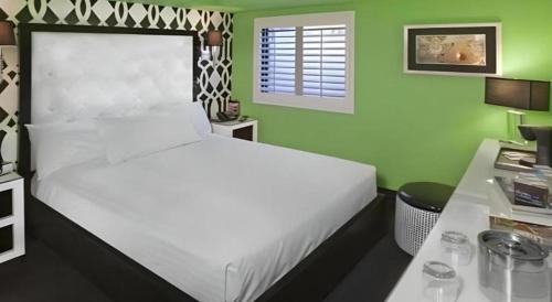 a bedroom with a white bed and a green wall at Cabana Suites at El Cortez in Las Vegas