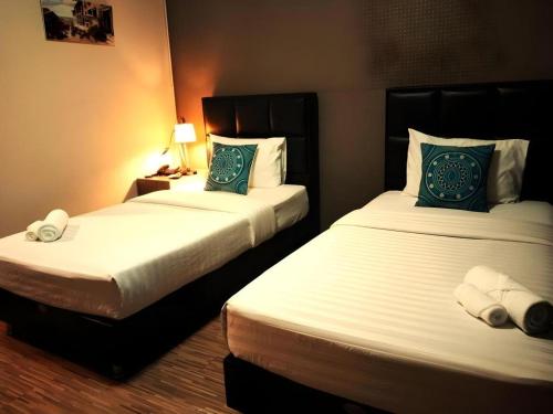 a hotel room with two beds and a lamp at V51 Hotel in Nakhon Ratchasima