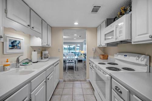 a kitchen with white appliances and a dining room at Beachy Vibes in Ponte Vedra Beach