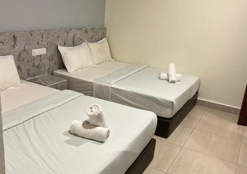 a hotel room with two beds with towels on them at D'Lima Beach Inn in Pantai Cenang