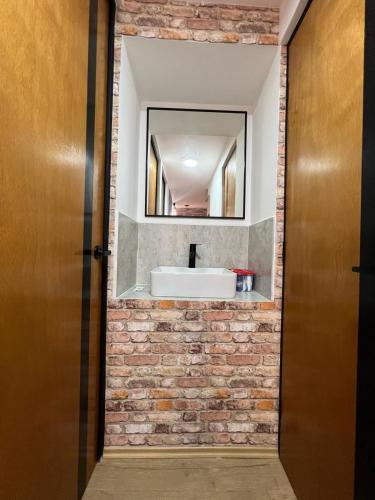 a bathroom with a sink and a mirror on a brick wall at Departamento Junto a la Feria de Pachuca in Pachuca de Soto