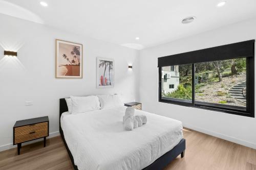 a white bedroom with a bed and a large window at Eleve Lorne in Lorne