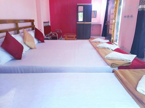 two beds in a room with red walls at Samant Beach Resort in Malvan