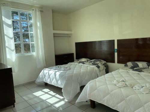 a bedroom with two beds and a window at Hotel Leilani in San Andrés Sinaxtla