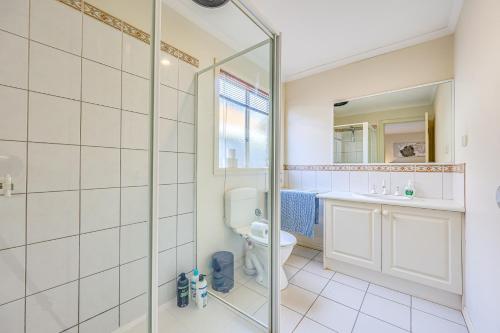 Un baño con ducha, inodoro y lavabo. en StayAU Family Retreat with Pool Table in Cranbourne, en Cranbourne
