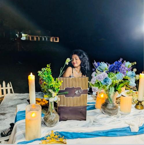 a woman sitting at a table with flowers and candles at Sea royal beach cafe in Virār