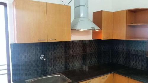 Una cocina con gabinetes de madera y un fregadero. en Abimayu Gardern, en Covelong