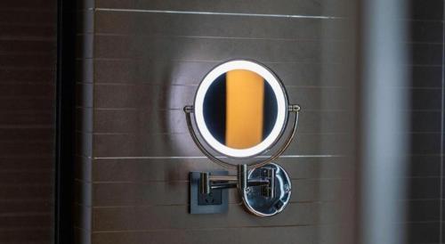a mirror on a bathroom wall with a sink at Xana Hotelle Shenzheng South Station Foxconn in Shenzhen