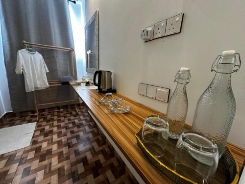 two glass bottles on a wooden counter with glasses on it at KANBULO House Maldives in Huraa