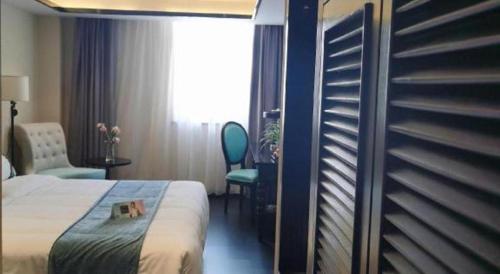 a hotel room with a bed and a chair and a window at Xana Hotelle Wuxi Railway Station Zhongshan Road in Wuxi