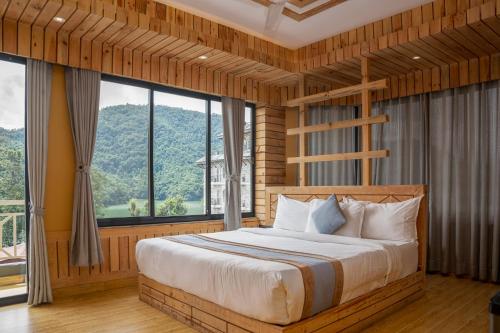 a bedroom with a bed with a large window at Trekkers Inn Boutique Hotel Pokhara in Pokhara