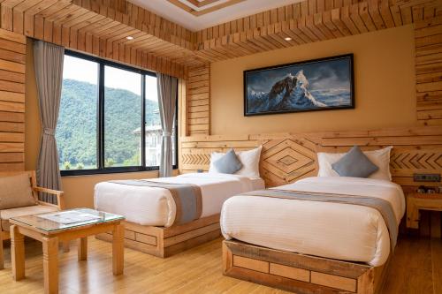 a hotel room with two beds and a chair at Trekkers Inn Boutique Hotel Pokhara in Pokhara