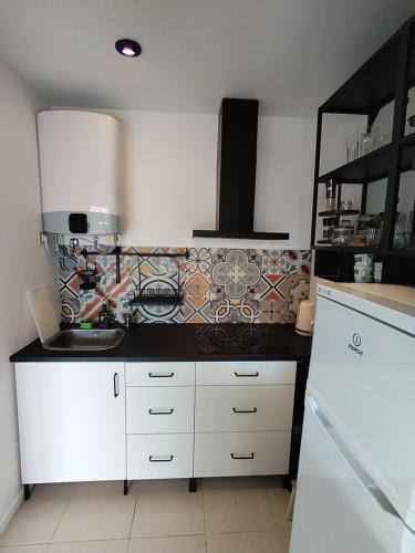 een keuken met witte kasten en een tegelmuur bij Tenerife Golf Park Apartment in San Miguel de Abona