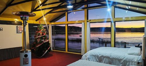 kantuta Lodge Uros في بونو: غرفة نوم مع شجرة عيد الميلاد ونافذة كبيرة