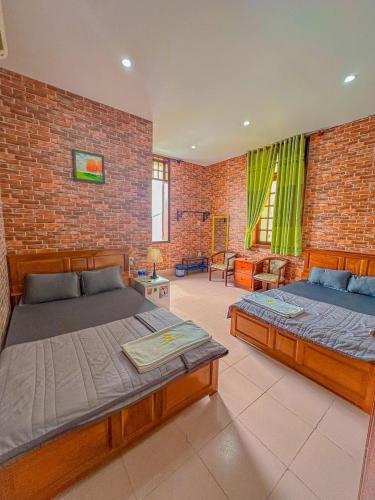 a bedroom with two beds and a brick wall at Cozy Home Cần Thơ in Can Tho