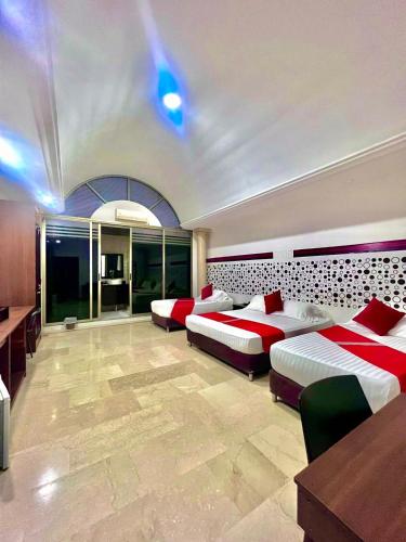 a large room with two beds and a table at Hotel Ingenio Reina Isabel in Cali