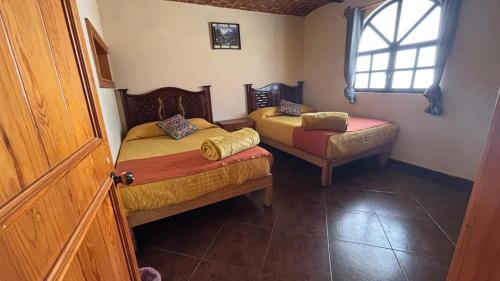 a small bedroom with two beds and a window at Hotel Santa Cecilia in Tapalpa