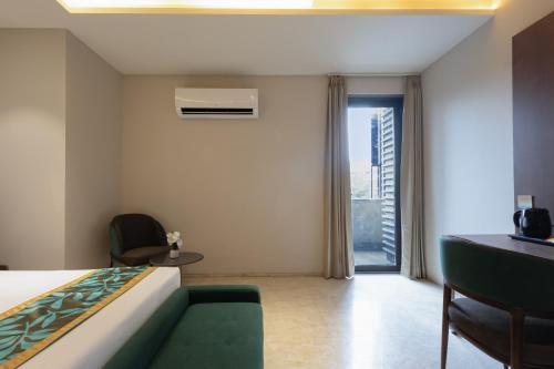 a bedroom with a bed and a couch and a window at Saltstayz Premier - Naraina, Central Delhi in New Delhi