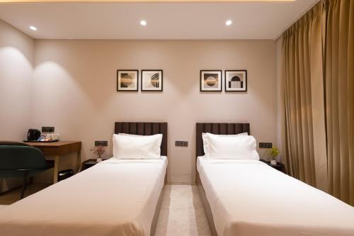 two beds in a hotel room with a desk at Saltstayz Premier - Naraina, Central Delhi in New Delhi