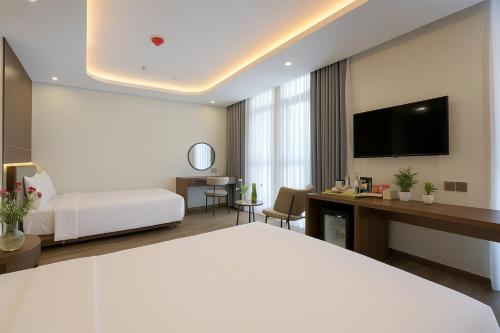 a hotel room with a bed and a desk with a tv at Nature Hotel - Lac Long Quan in Hanoi
