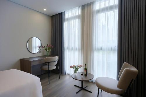 a hotel room with a bed and a table and a mirror at Nature Hotel - Lac Long Quan in Hanoi