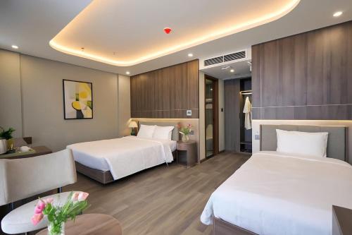 a hotel room with two beds and a table at Nature Hotel - Lac Long Quan in Hanoi