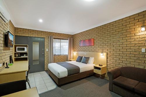 a hotel room with a bed and a desk and a couch at Sunray Motor Inn in Toowoomba