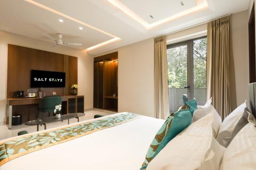 a bedroom with a white bed and a television at Saltstayz Premier - Naraina, Central Delhi in New Delhi