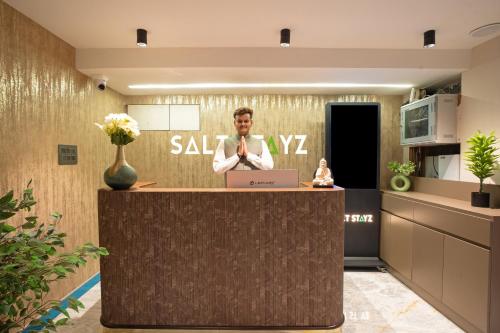 a man is standing at a counter in a lobby at Saltstayz Premier - Naraina, Central Delhi in New Delhi