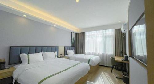 a hotel room with two beds and a television at GreenTree Inn Express Qingdao Jiaodong International Airport in Qingdao