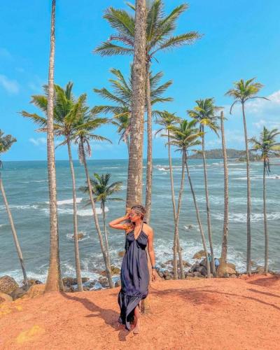 a woman walking on the beach with palm trees at Amible Guest Home in Mirissa