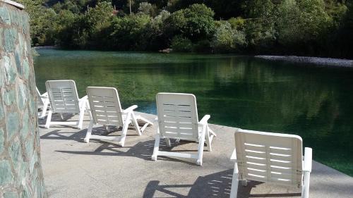 a row of lawn chairs next to a pool of water at Motel and Restaurant Odušak in Drežnjak