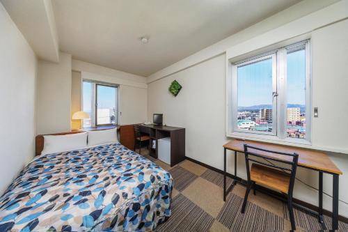 a bedroom with a bed and a desk and windows at Mizusawa Green Hotel in Oshu