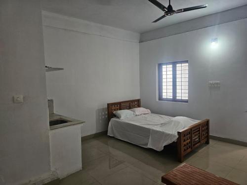 Un dormitorio con una cama y un ventilador de techo. en Kuniya Arcade Stay, en Kasaragod