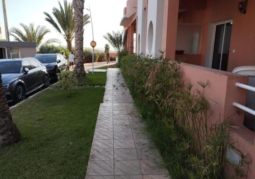 a sidewalk next to a house with cars parked at Elegant Seaside Retreat 80m from Beach, Pool & BBQ in Aghroude
