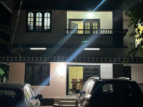 two cars parked in front of a house at night at Bluebell Homes in Beypore