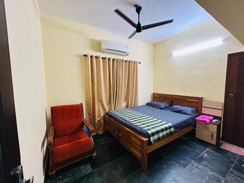 a bedroom with a bed and a red chair at Bluebell Homes A - 3 BHK Near to Calicut in Beypore