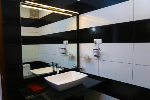 a black and white bathroom with a sink and a mirror at The Dorwin Heights in Kandy