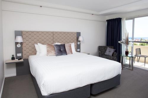 a bedroom with a large white bed and a chair at The Lord Forrest Hotel in Bunbury