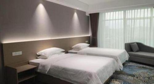 a hotel room with two beds and a chair at Grand Nest Hotel (Tang Jia Wan Beach) in Zhuhai