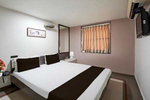 a bedroom with a large white bed and a window at Super Collection O Sachivalaya Metro Station Gandhinagar Formerly Hotel Ghunghat Inn in Gandhinagar